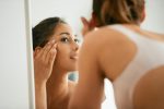 Woman looking at eye area in mirror