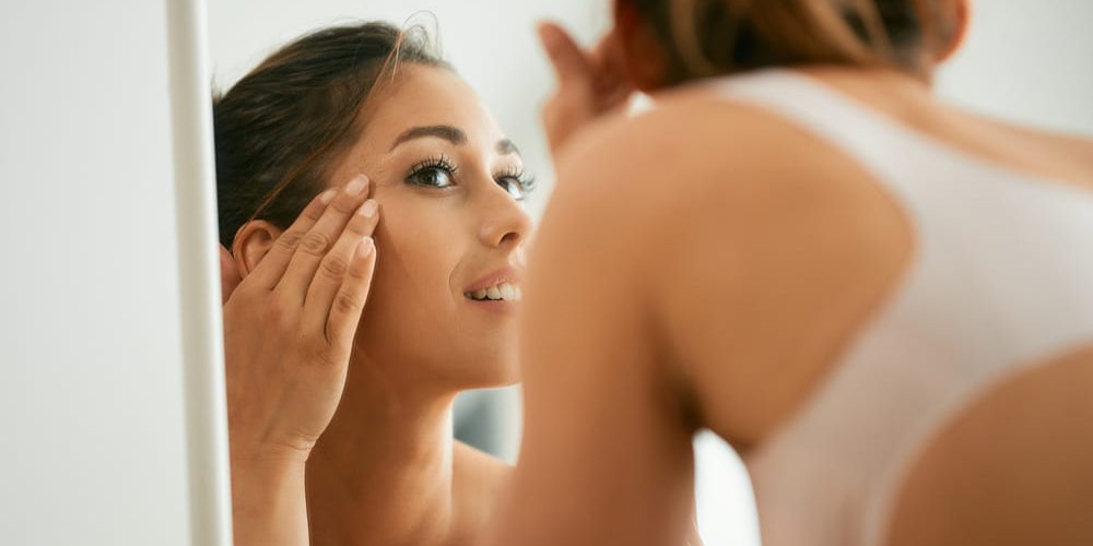 Woman looking at eye area in mirror