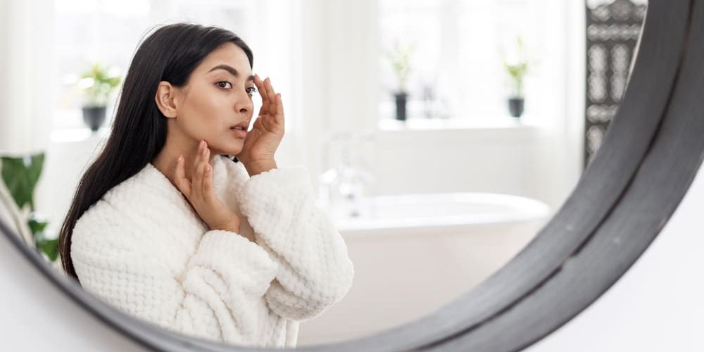 Woman looking at skin in mirror